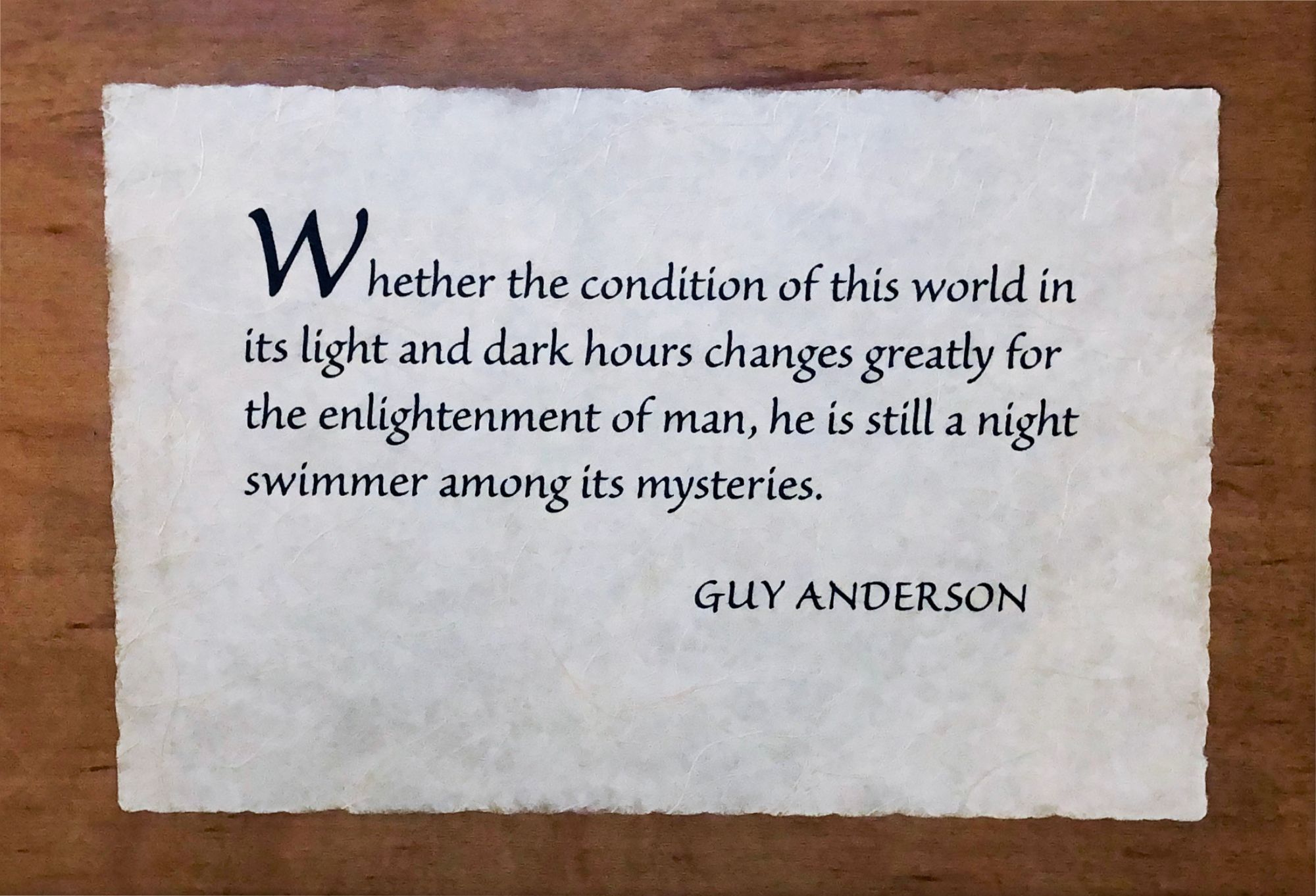 Photo of wooden plaque with Guy Anderson quote: “Whether the condition of this world in its light and dark hours changes greatly for the enlightenment of man, he is still a night swimmer among its mysteries.” 