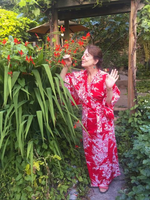 Sandra in a red yukata in her Seattle garden, smelling Croscosmia flowers, July 2016, by David BIlides
