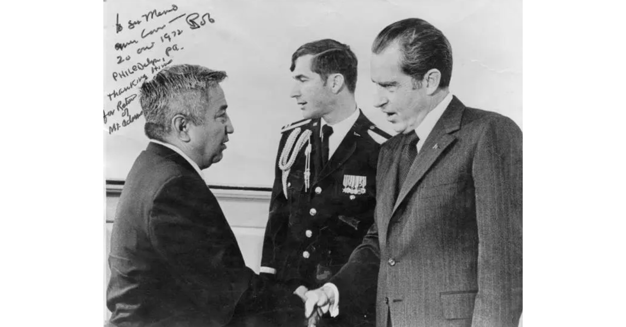 Photo of Nixon on right shaking hands with Yakama leader on left, with unknown man in epaulets in center
