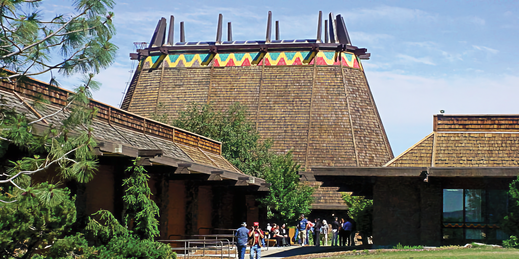 Photo of large building in center with trapezoidal shape and colored bunting, with two lower buildings on either side