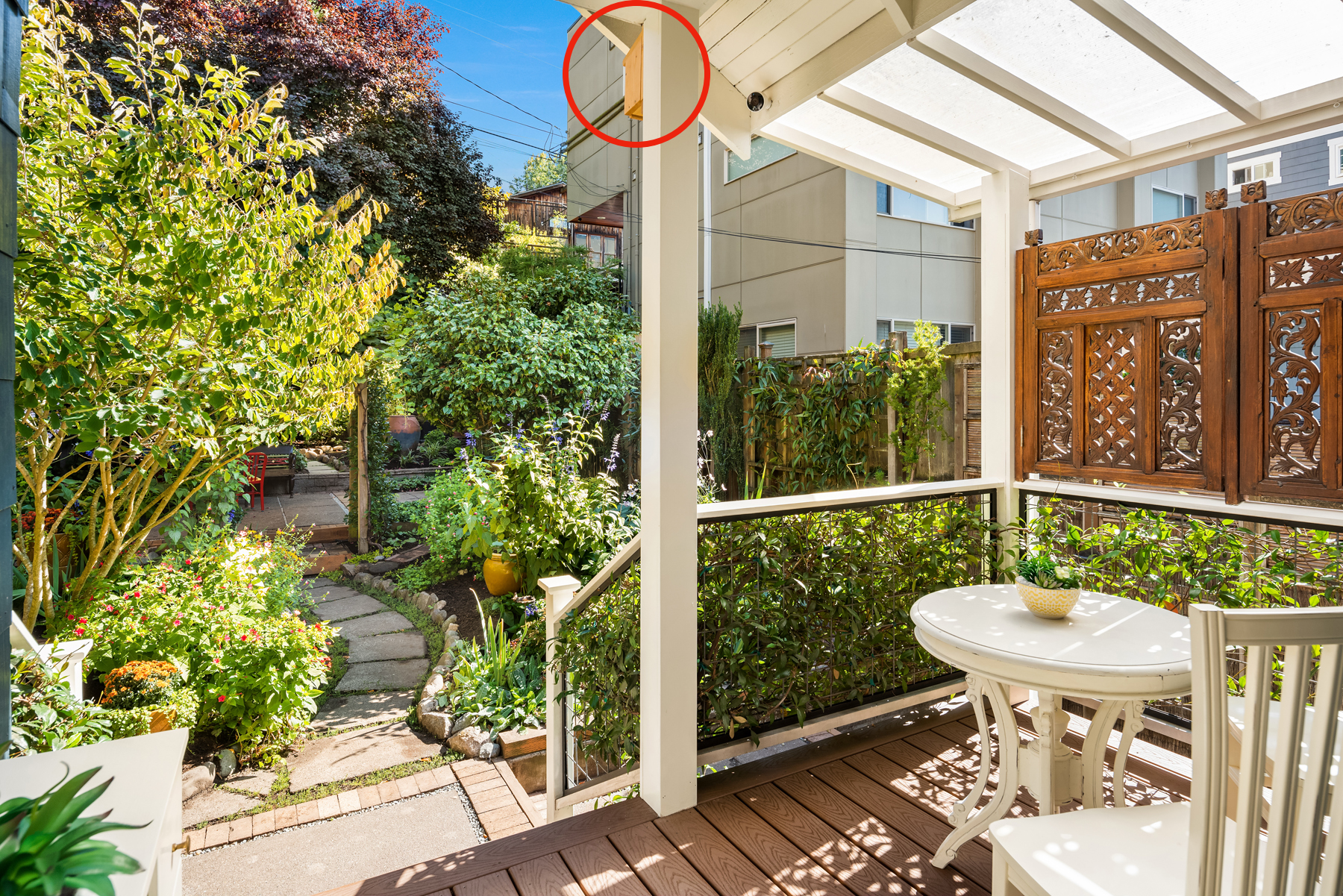 Photo of backyard garden with wooden porch, white table and chair, and carved wooden panels