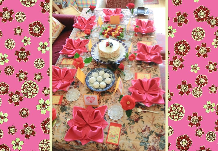 Photo of elaborate place settings on table with pink fuschia napkins, fruit, white cake, and tea cookies.